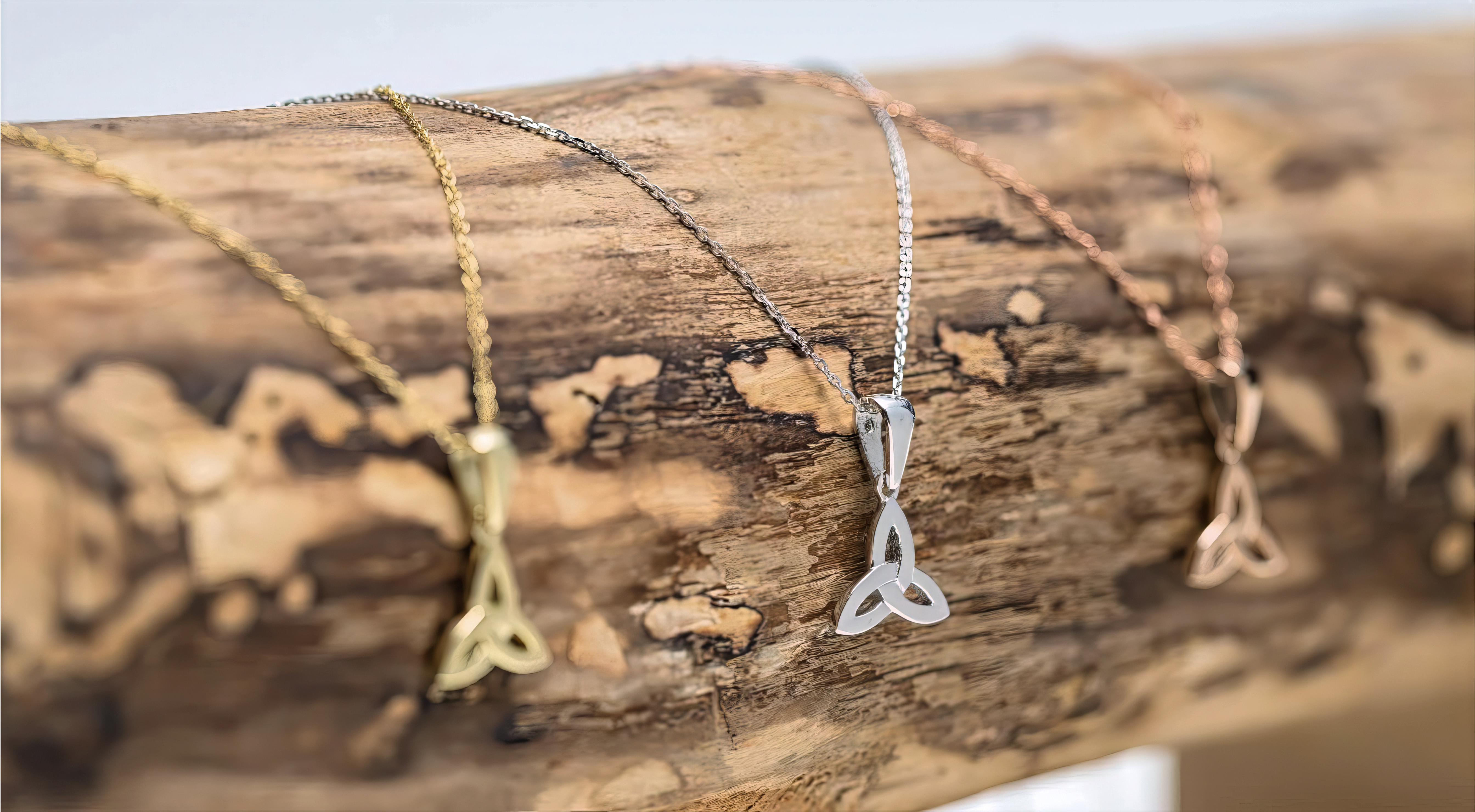 Trinity Knot pendants in gold, silver, and rose gold, three interlocking loops symbolizing eternity